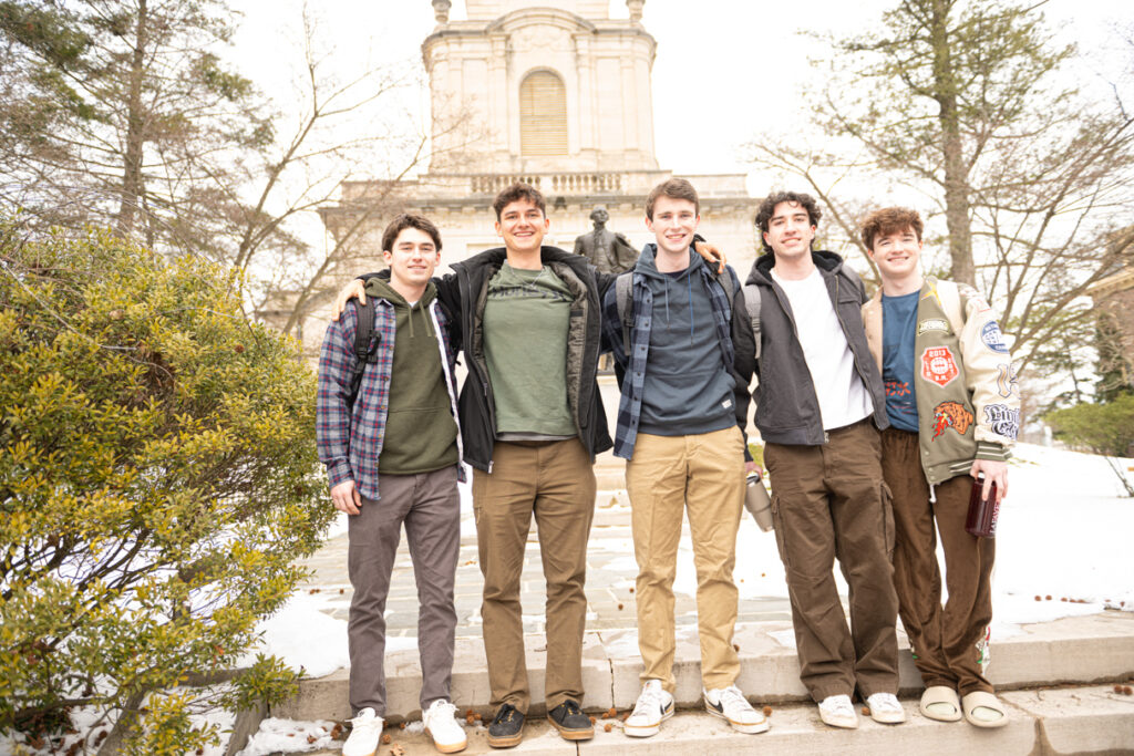Five students stand side by side and pose for a photo in front of Colton Chapel.