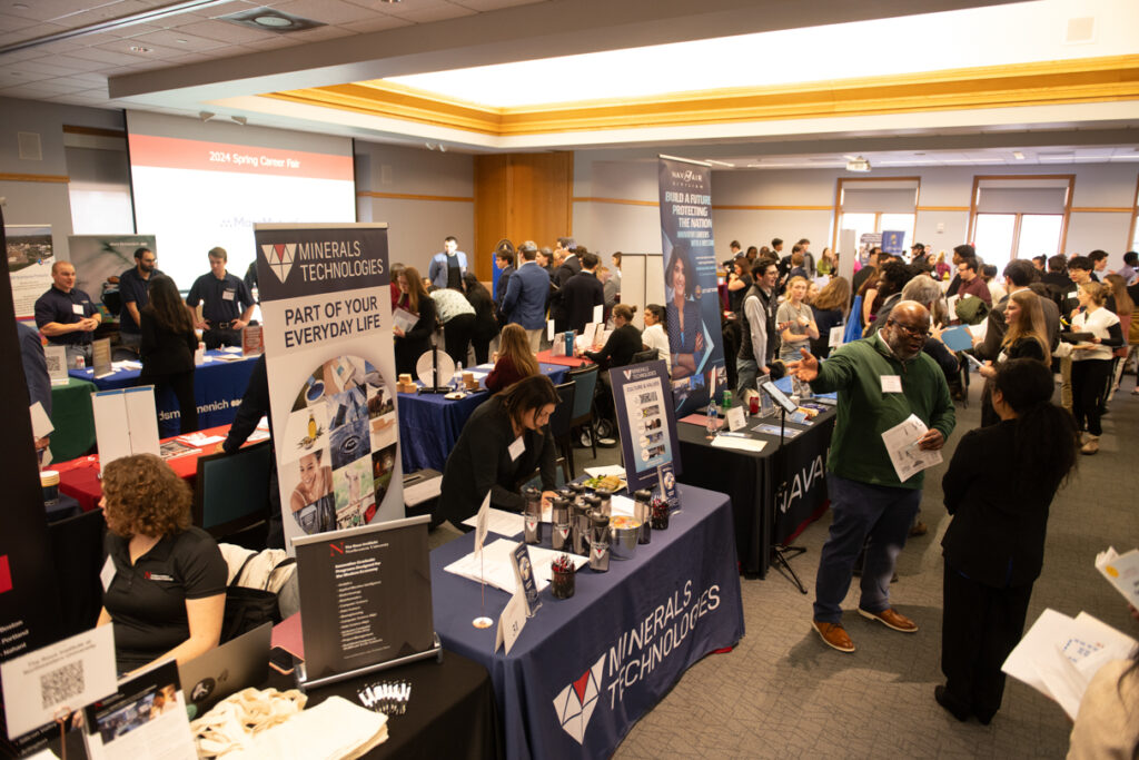 A large room full of booths and people networking.
