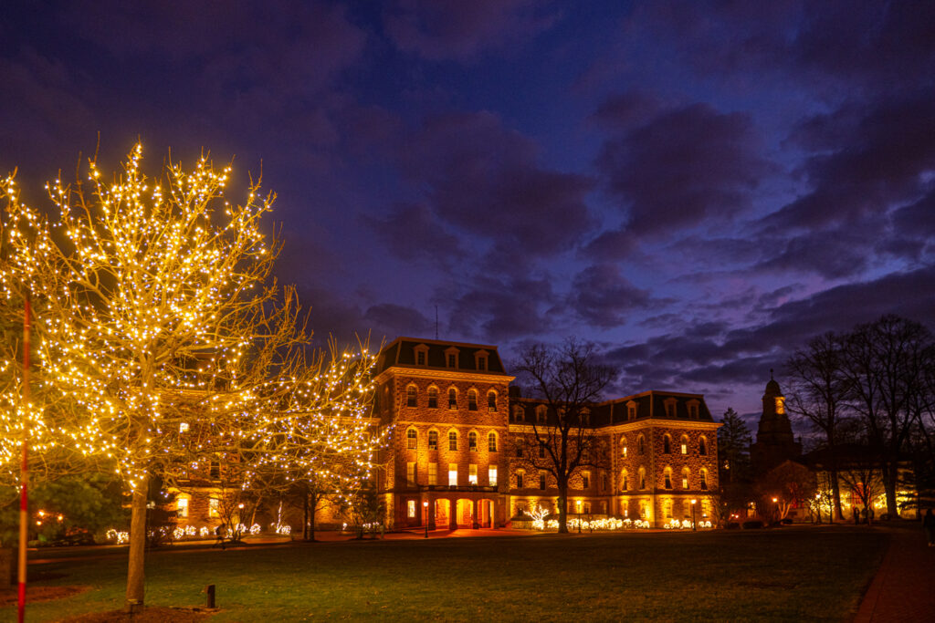 A wide shot of Pardee Hall at night lit up with lights and a stormy sky.