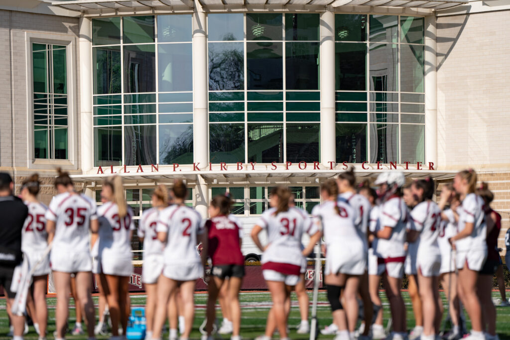 The Lafayette womens Lacrosse team stands in Fisher Stadium with Kirby Sports Complex in focus in the background.