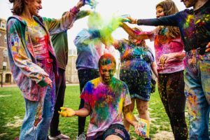 Students drop multicolor powder on a student on the Quad during Holi