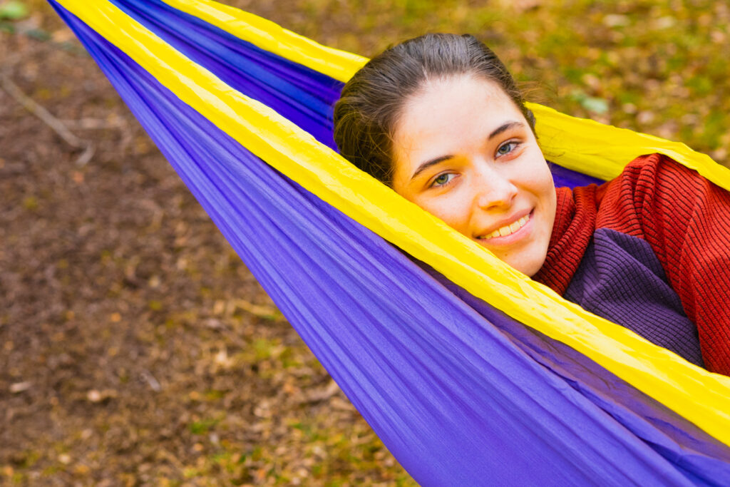 Close up of a person's head sticking out of a hammock smiling.