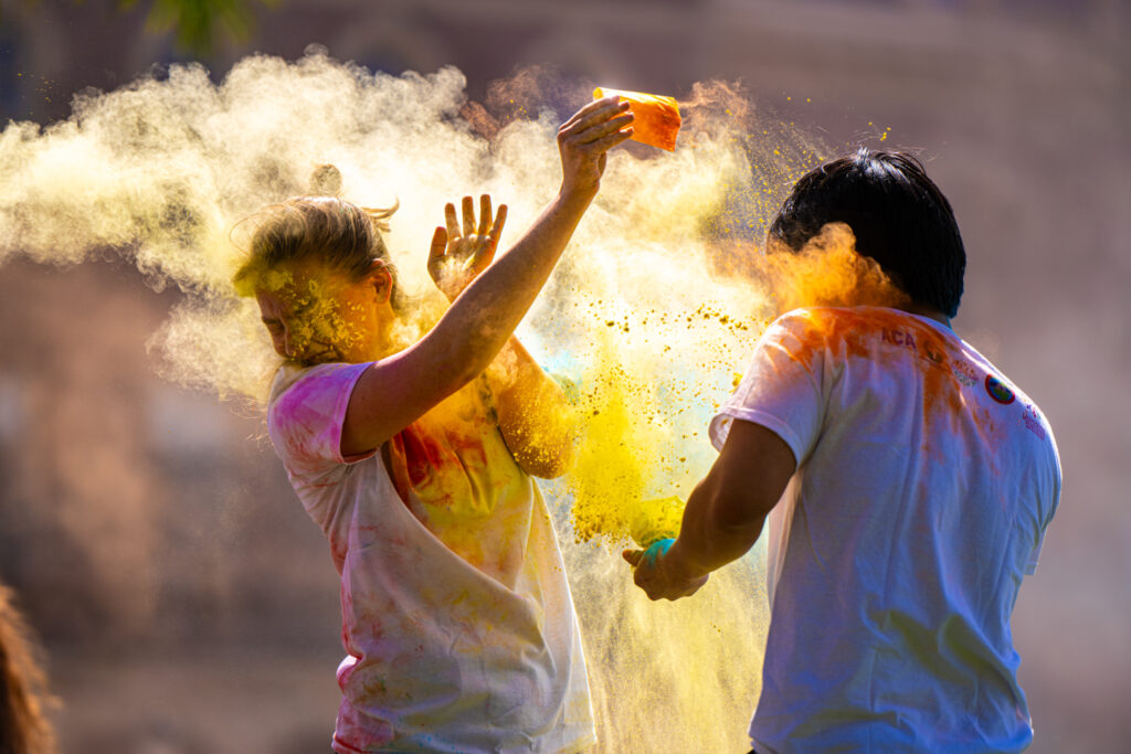 One person throws yellow powder ay another person.
