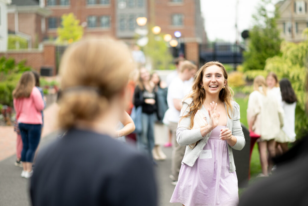 A young woman waves to the president of Lafayette College at a garden party.