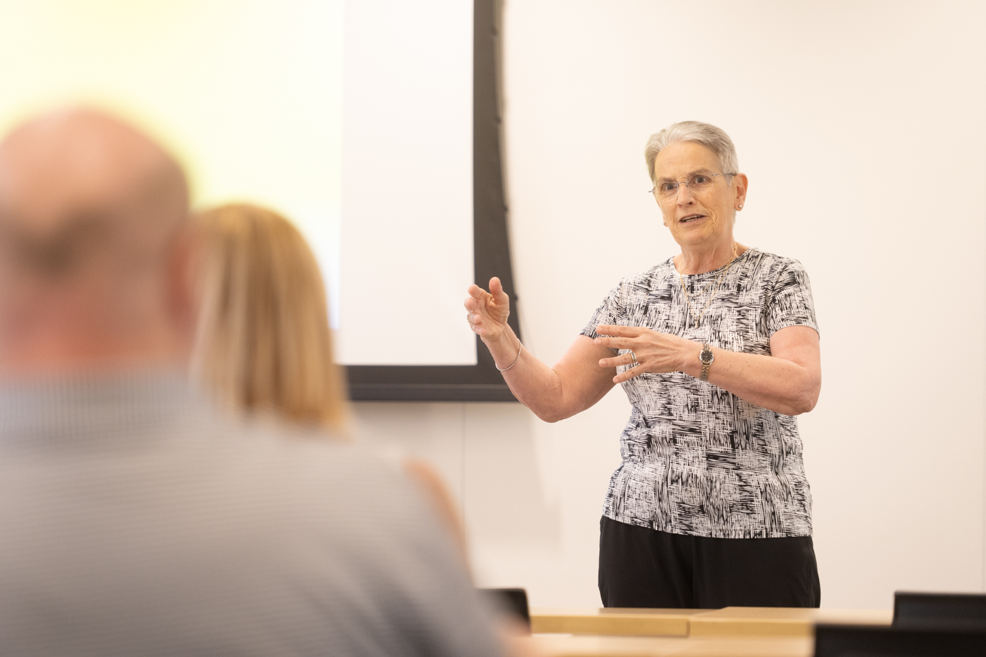 A woman professor lectures to a class of older alumni