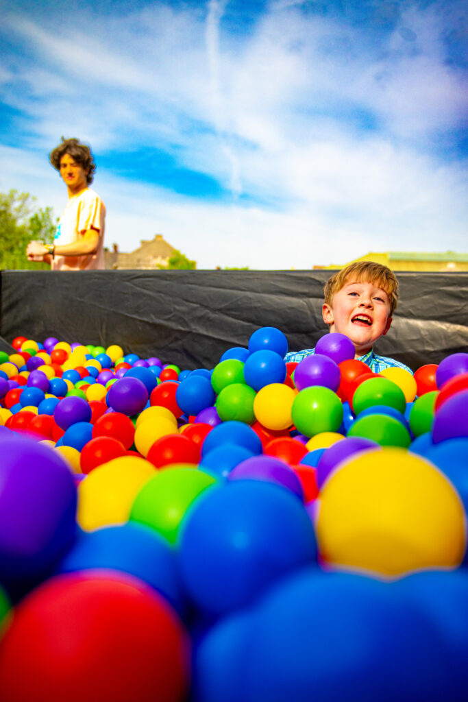 A child's head pokes out of a colorful plastic ball pit.