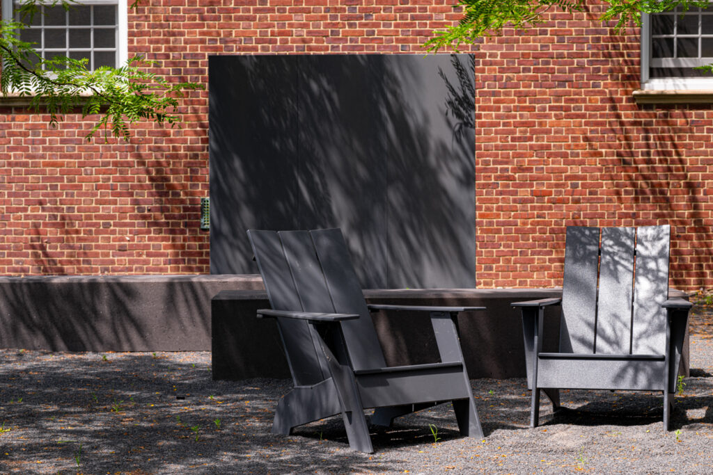 Two empty slate chairs in a partially shaded courtyard. 