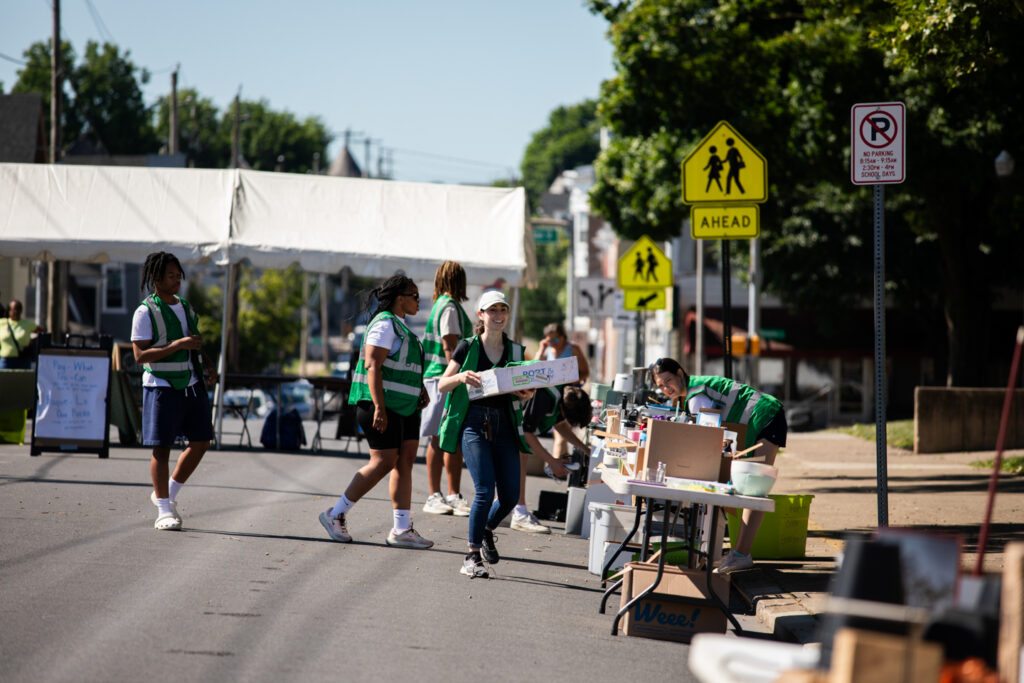 Volunteers in green vests set up tables of donations.