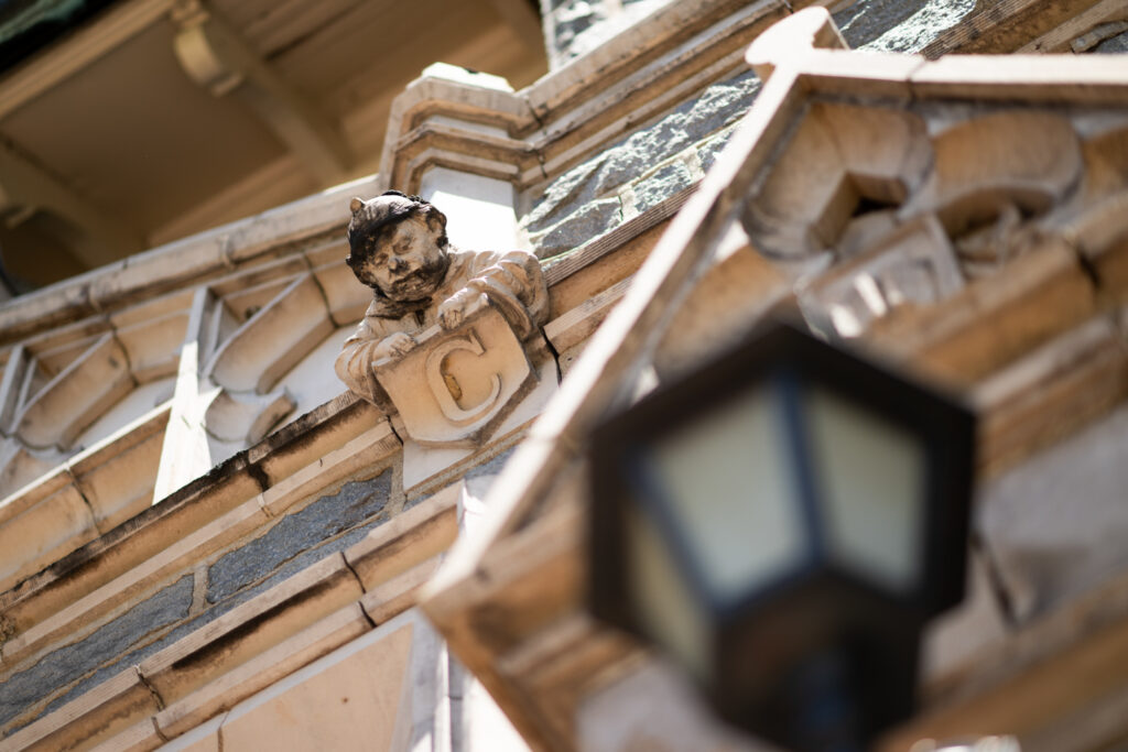 Close up of a building facade featuring a figure and the letter "Y" carved in stone.