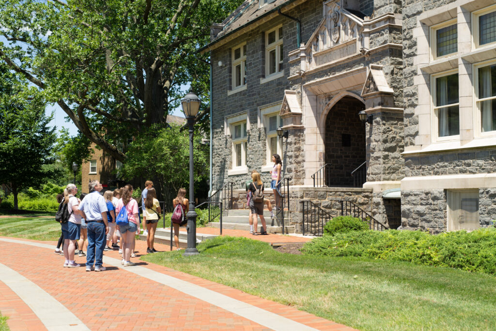 A group of people gathered in front of Hogg Hall on a sunny day.