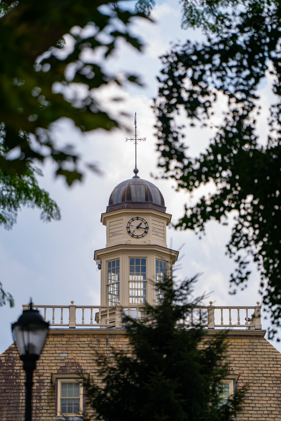 The cupola of Kirby House is visible through the leaves of trees that line the path outside of the residence hall. 