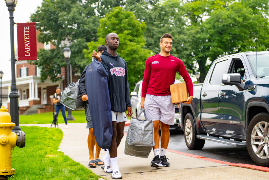 Two students carry luggage and boxes as part of Move-in 2023