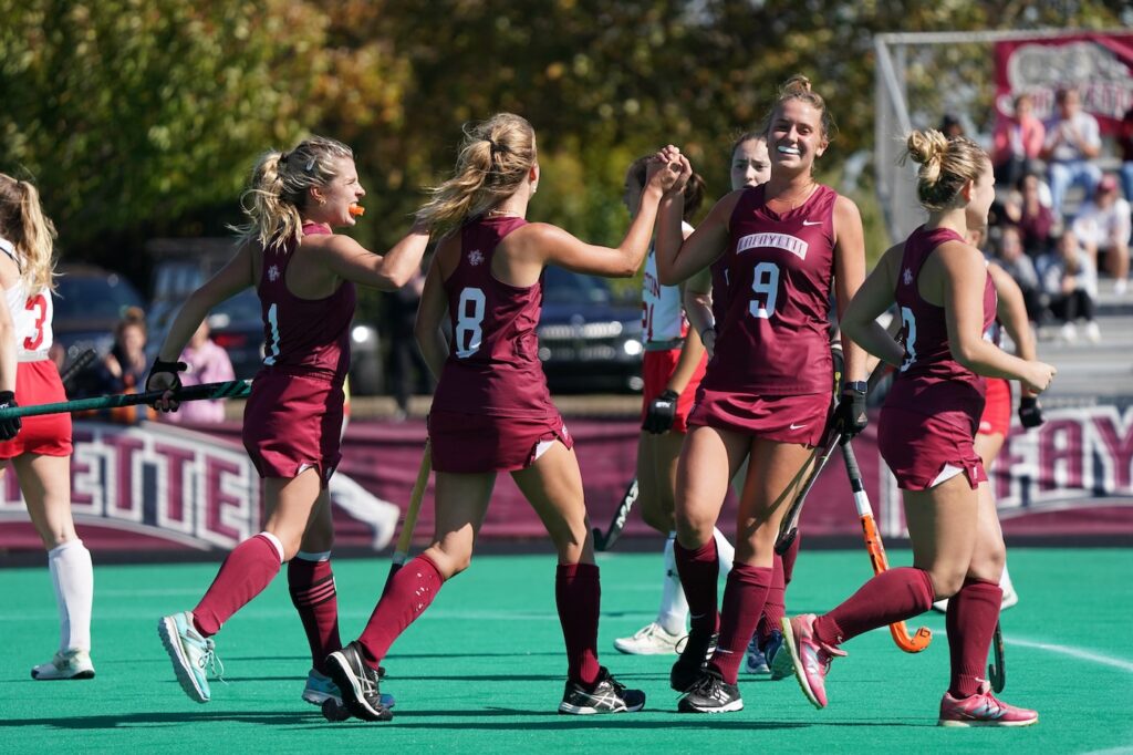 The field hockey team high fives on the field