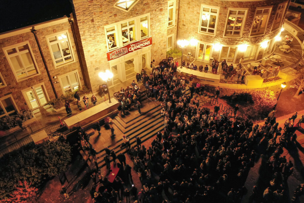 An aerial shot of a group of people gathered in front of Farinon College Center at night.