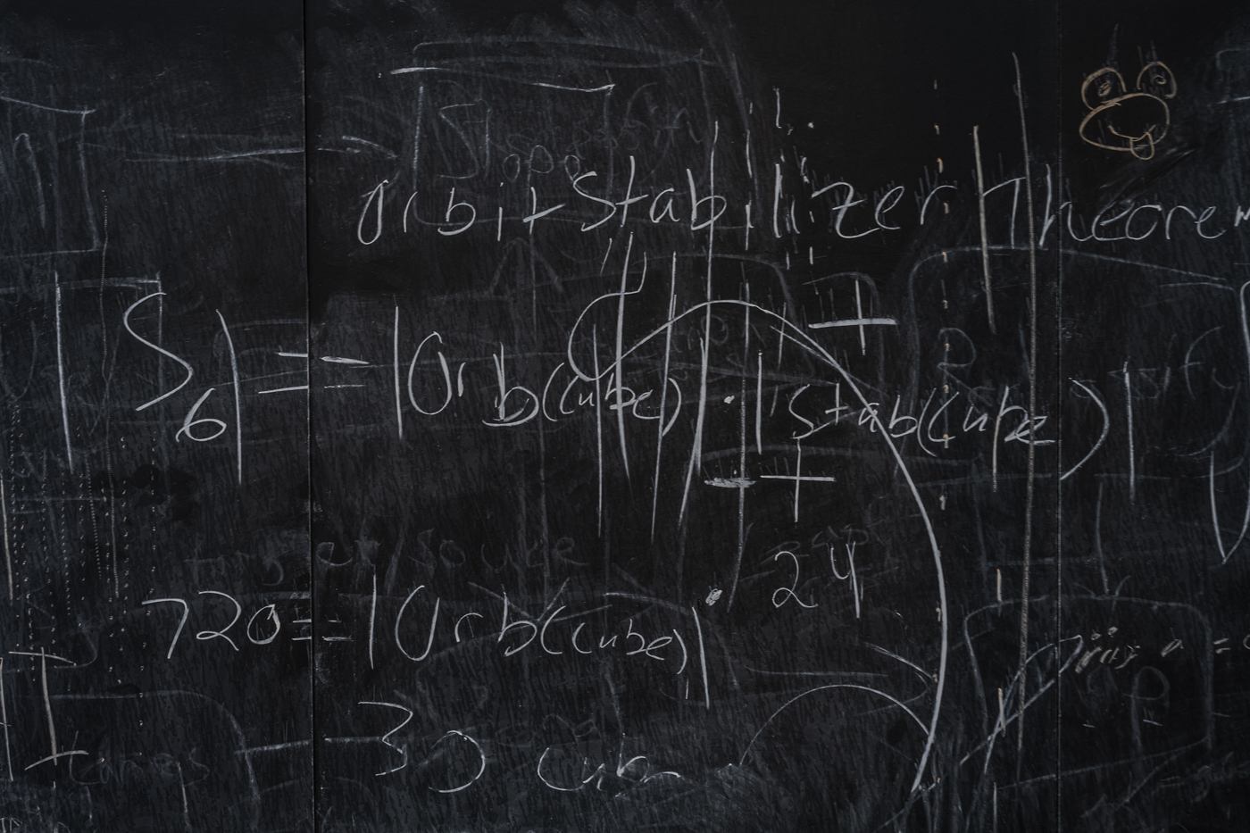 Various equations and other statements have been hastily written on an outdoor chalk board