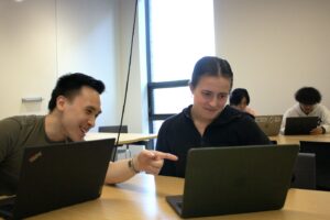 Lucy McShane ‘25, Computer Science and Women and Gender Studies double major, and Nathan Dihn ‘25, Computer Science major, look over computers as they're studying inside RISC.