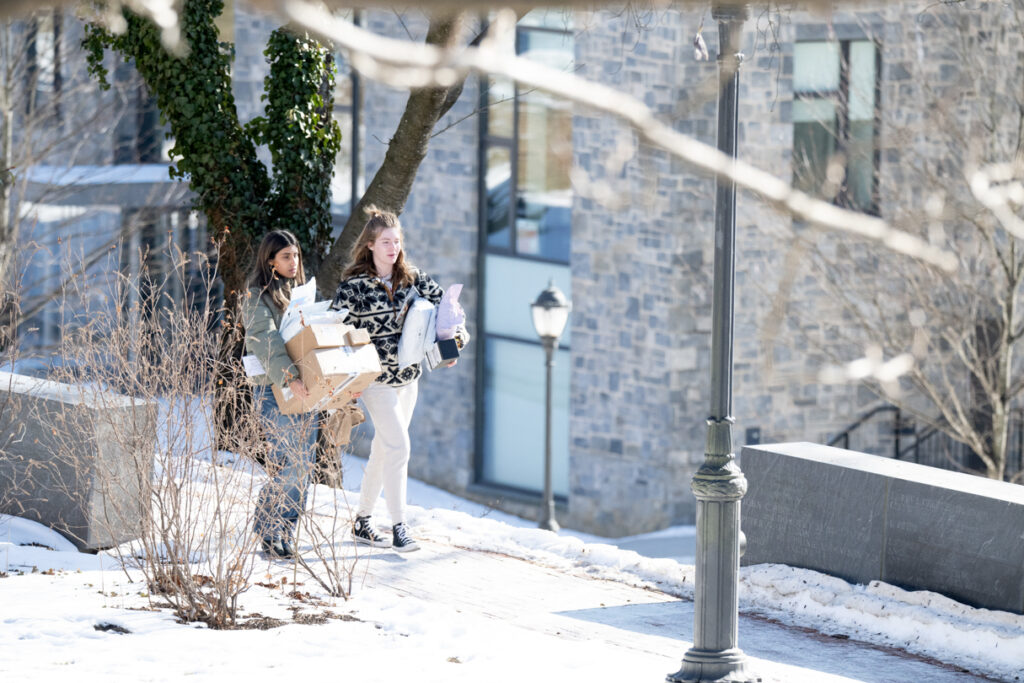 Two people walking with arms full of packages.