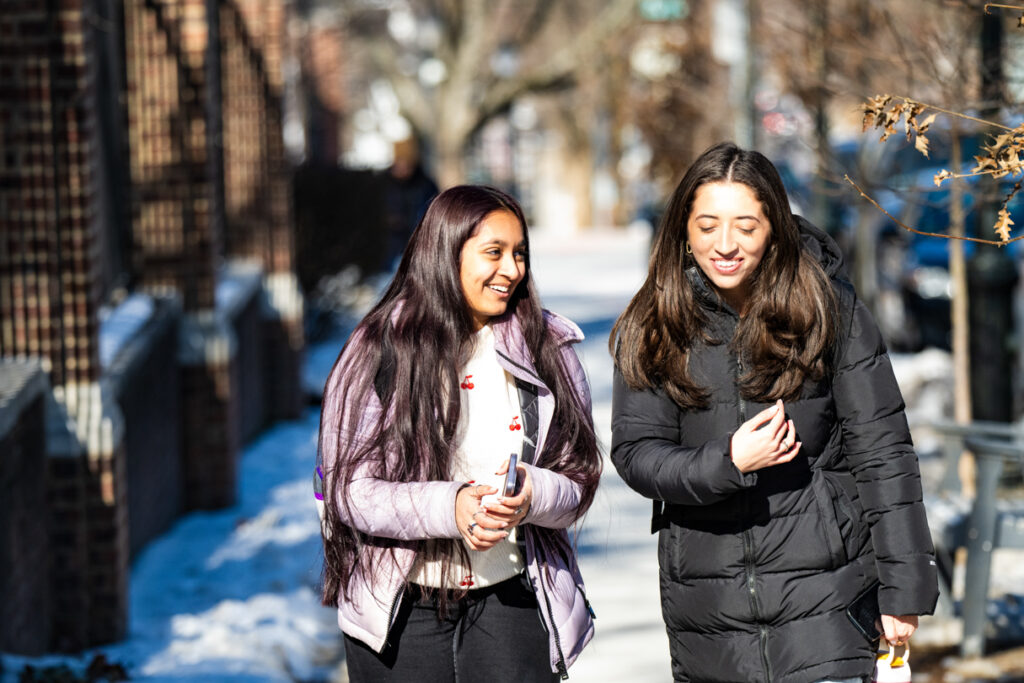 Two people walk along side each other smiling.