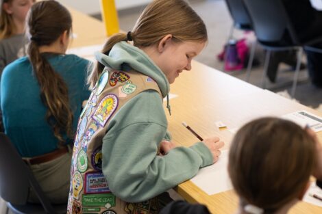 A girl scout smiles as she works on part of her badge lesson.