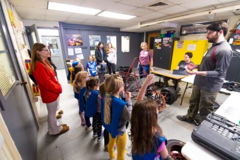 Dean Lauren Anderson, Lafayette volunteers show Girl Scouts the parts of a car in Acopian.