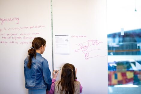 Two Girl Scouts draw out their ideas on a white board during a Stem Career Exploration session.