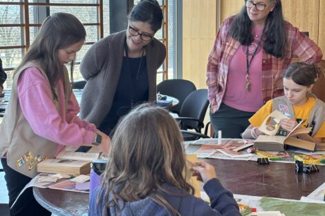 Girl Scouts learn from Beth Sica and Ana Ramirez Luhrs as they work on a Book Artist project in the library.