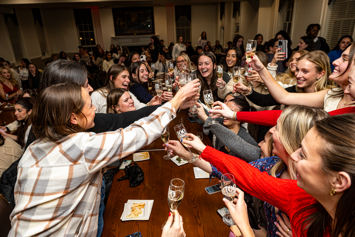 A group of college students toast champagne glasses in a ballroom.