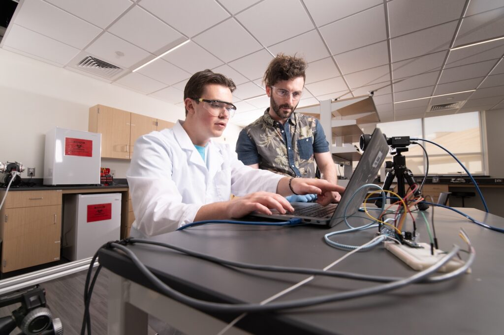 Prof. Ryan Rosario works in a lab with a student.