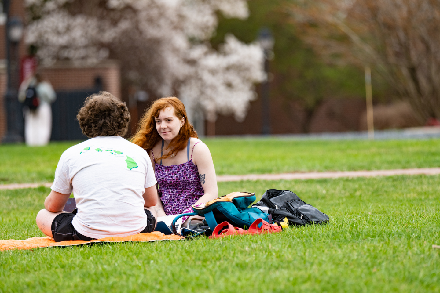 Two students sitting on a big grassy field at Lafayette College, studying together on a pleasant spring day. 