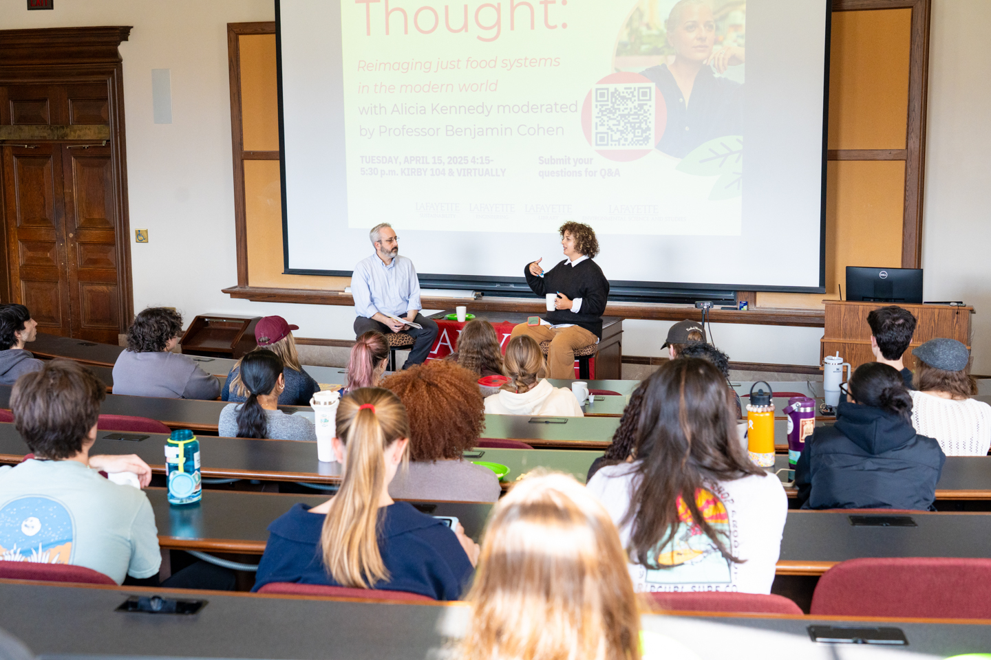 Professor Ben Cohen and keynote speaker Alicia Kennedy in front of an audience, discussing themes from her book "No Meat Required: The Cultural History and Culinary Future of Plant-Based Eating"