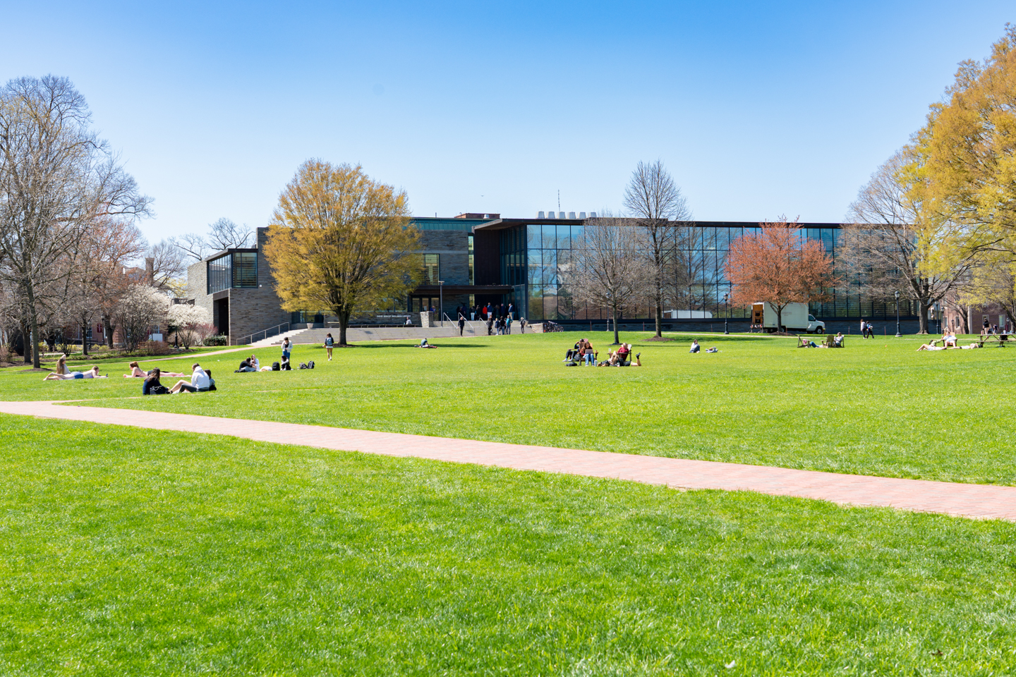 Skillman Library at Lafayette College, with a big grassy field in front filled with students enjoying the beautiful weather.