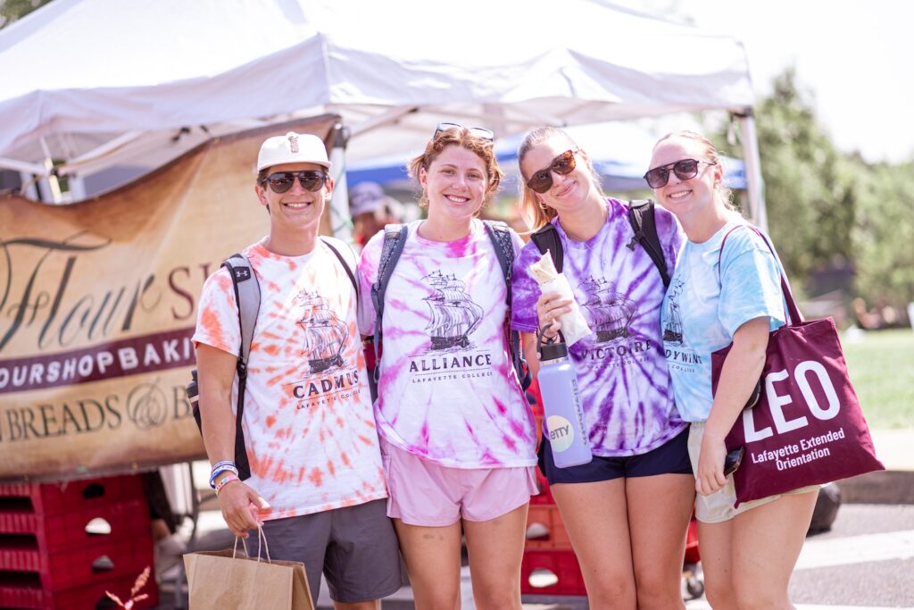 A group of four LEOs in tie dye t-shirts are shown at Easton Farmers' Market during 2024 Orientation