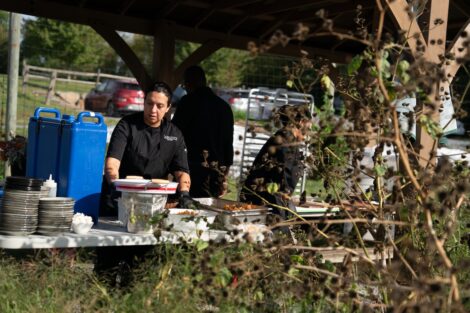 Dining team members Lady Amaya, Dayimin Duarte, Becker Charriot work under a canopy at LaFarm preparing a farm to table breakfast