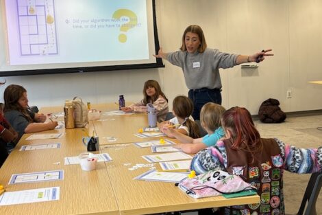 Lauren Biernacki gestures to the group as she presents a coding badge to Girl Scouts.