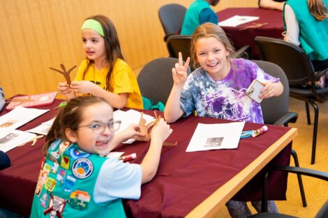 Three scouts make silly faces and show a peace sign for the camera. They're seated in Gendebien Room working on their playing the past badge.