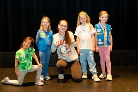 Four daisy scouts pose on stage in Williams Arts Center with a Lafayette student during the Art and Design Badge.