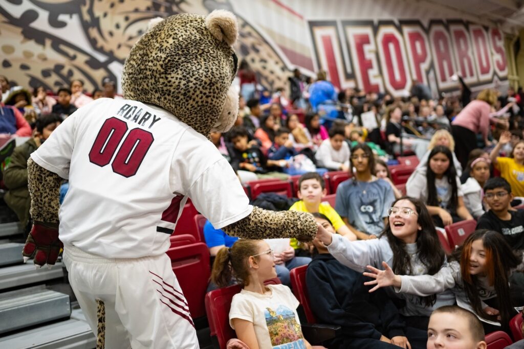 Roary the Leopard mascot high fives Easton Area fifth and sixth graders in the stands of Kirby Sports Center during the annual School Day Game.