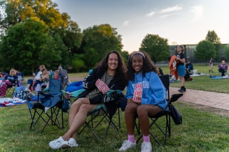 A woman and girl sit with popcorn bags in hand, ready for Movies on the Quad.