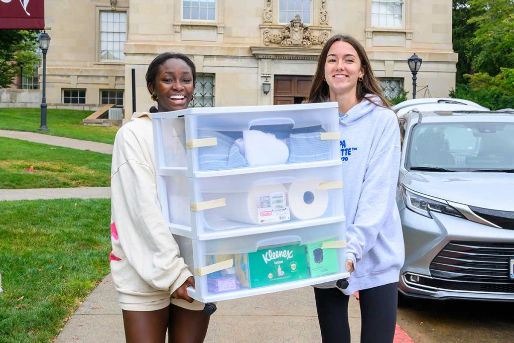 Two students working together to carry items to their campus residence
