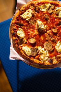 A view of a pizza from Colonial Pizza & Spaghetti House covered in ricotta and meatballs